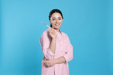 Photo of Woman with paintbrush on light blue background. Young artist
