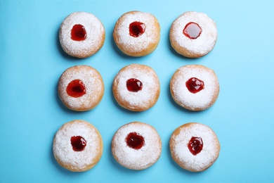 Photo of Hanukkah doughnuts with jelly and sugar powder 
on blue background, flat lay