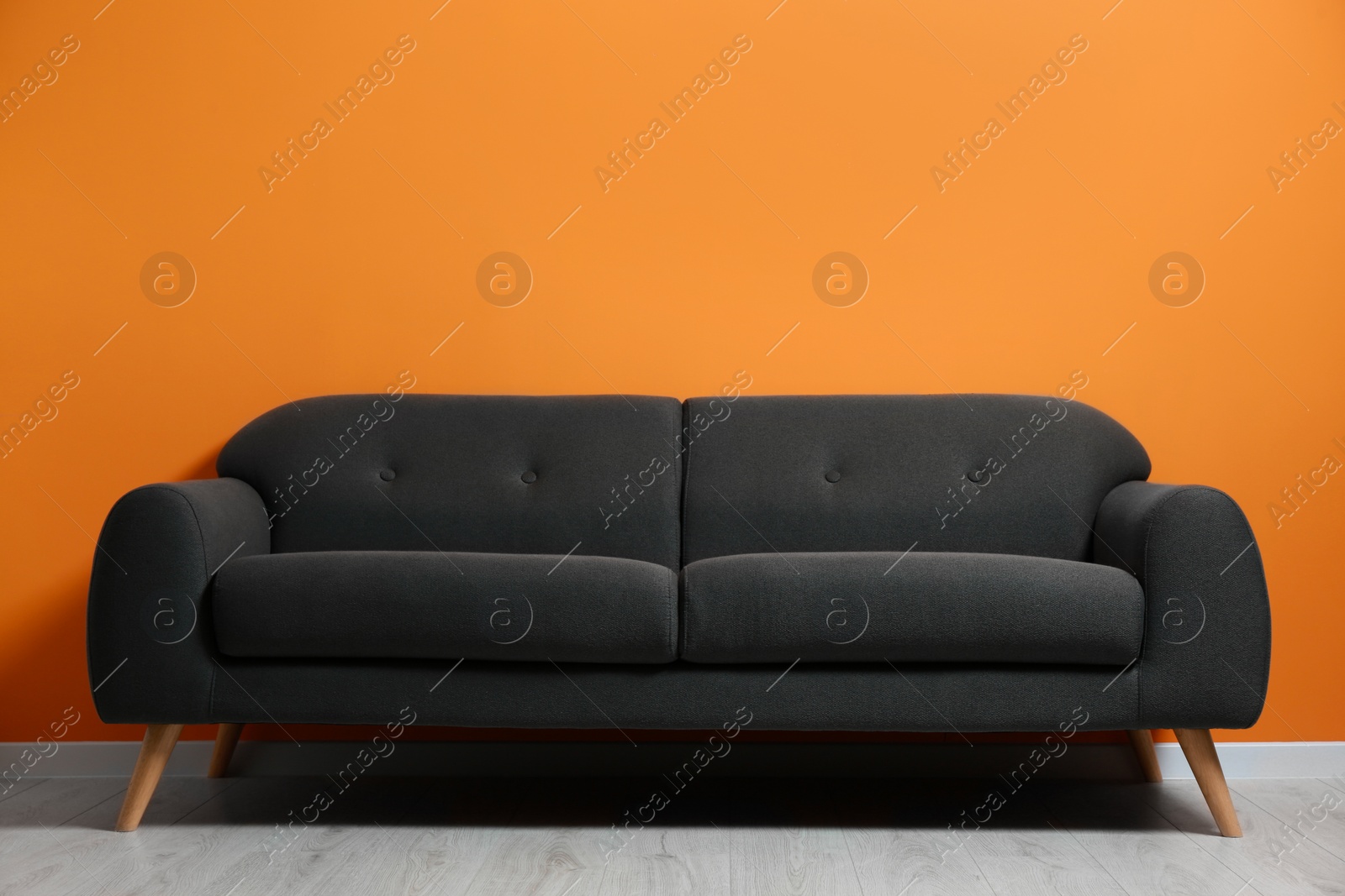 Photo of Stylish room with cosy sofa near orange wall. Interior design