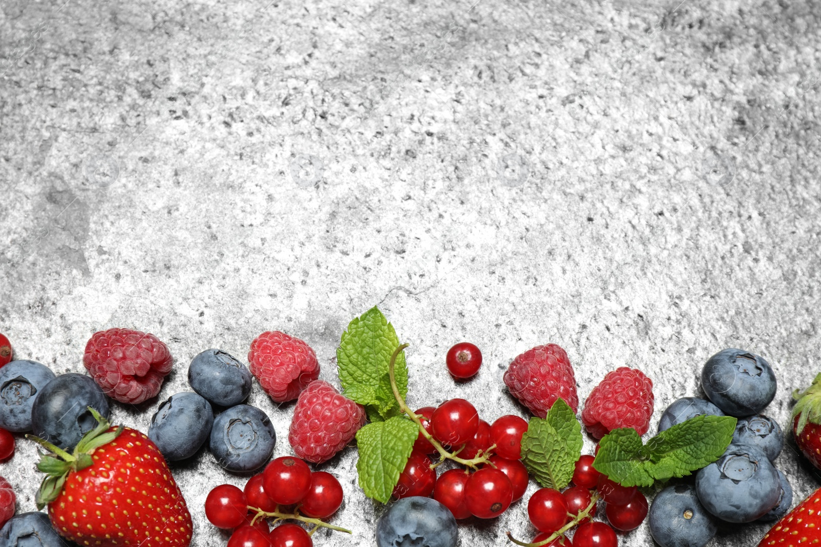 Photo of Different fresh berries on grey background, flat lay. Space for text