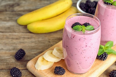 Photo of Delicious blackberry smoothie on wooden table, space for text