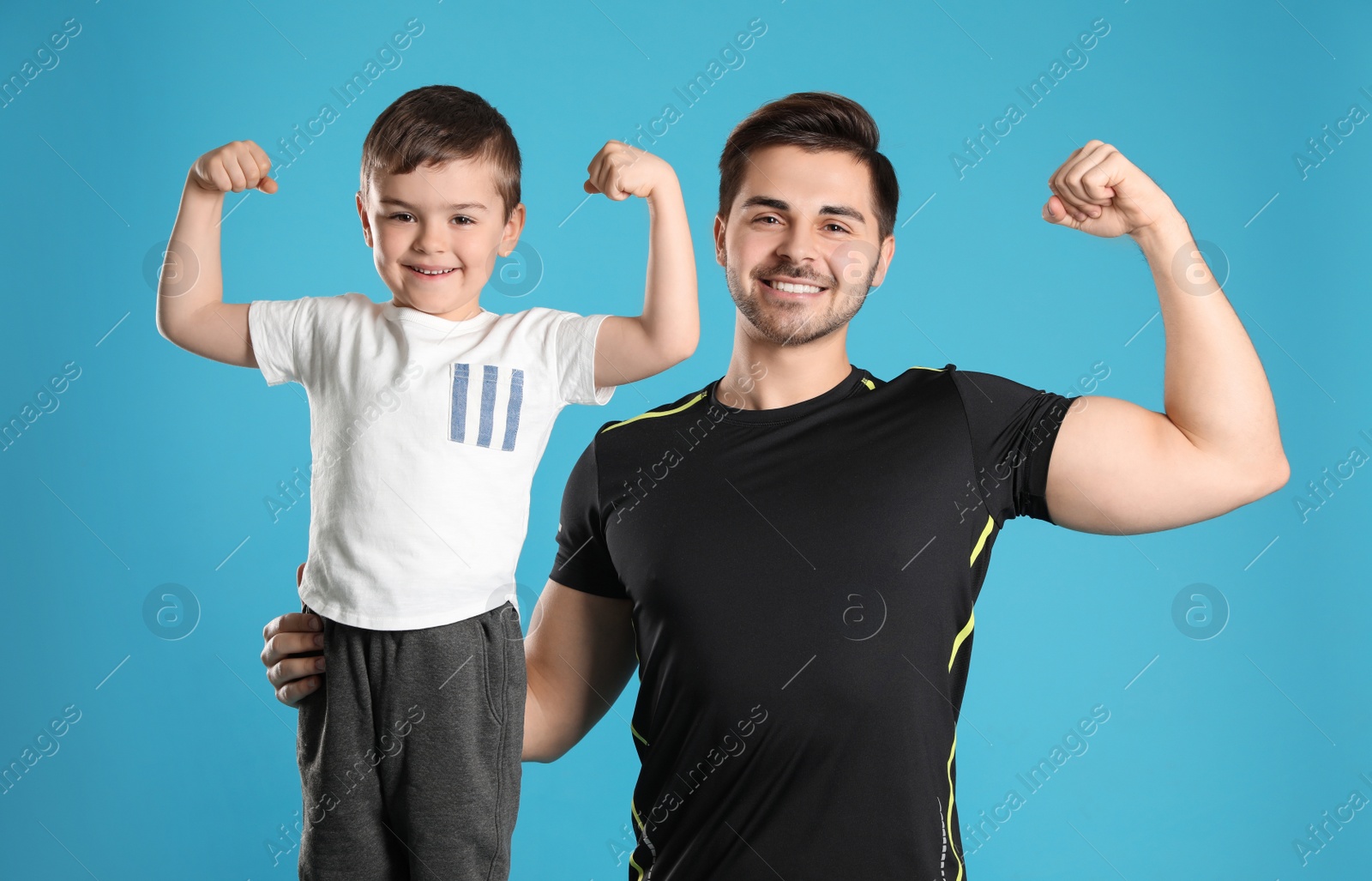 Photo of Portrait of sporty dad and his son on color background