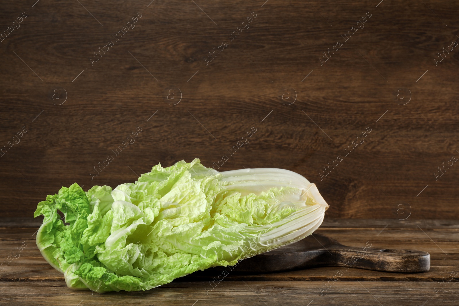 Photo of Cut fresh ripe Chinese cabbage on table against wooden background