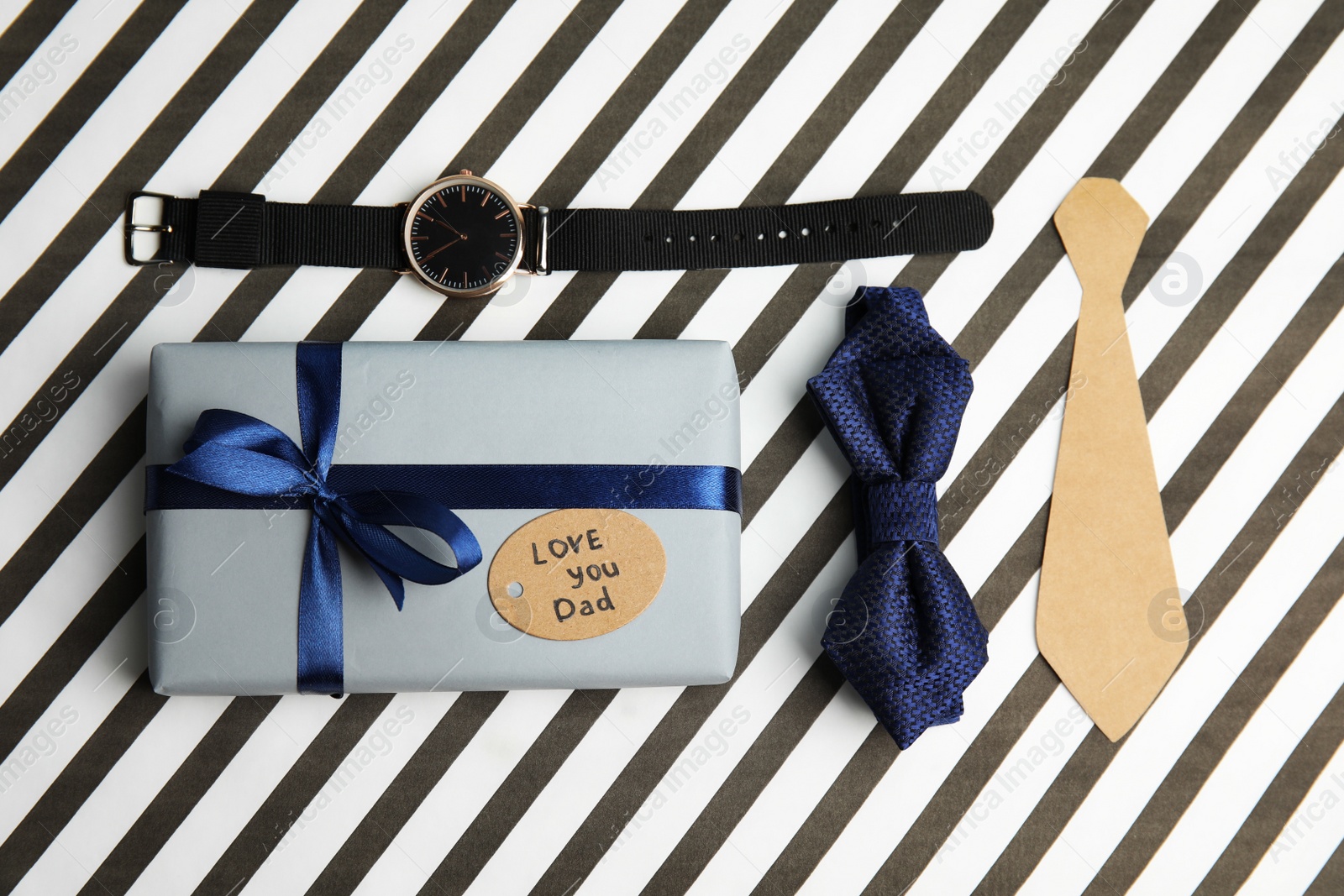 Photo of Flat lay composition with gift box and bow tie on striped background. Happy father's day