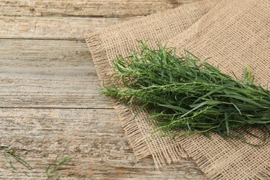 Photo of Fresh tarragon sprigs on wooden table. Space for text