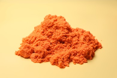 Photo of Pile of orange kinetic sand on beige background, closeup