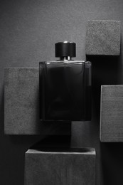Photo of Stylish presentation of luxury men`s perfume in bottle on black background, top view