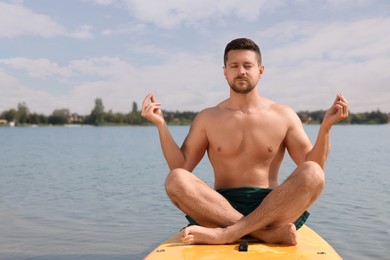 Photo of Man practicing yoga on SUP board on river, space for text