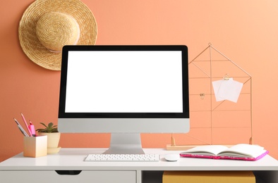 Photo of Comfortable workplace with modern computer on table near orange wall. Space for design