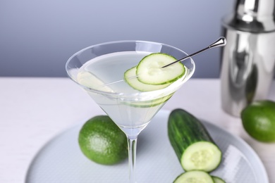 Composition with glass of cucumber martini on table against color background, closeup