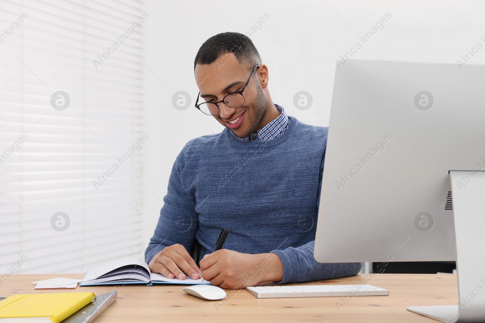 Photo of Happy young intern working at table in modern office