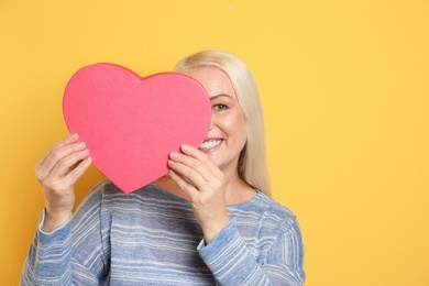 Photo of Portrait of mature woman with decorative heart on color background