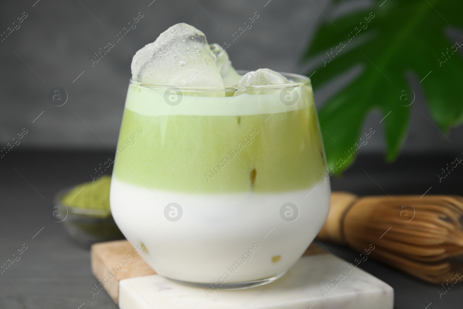 Photo of Glass of tasty iced matcha latte on grey wooden table, closeup