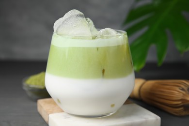 Photo of Glass of tasty iced matcha latte on grey wooden table, closeup