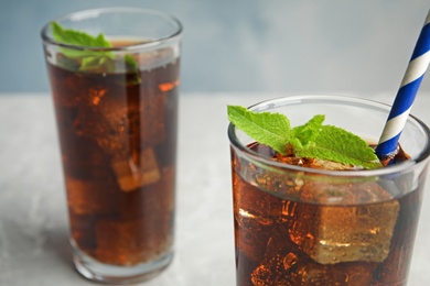 Refreshing soda drinks with ice cubes on table, closeup. Space for text