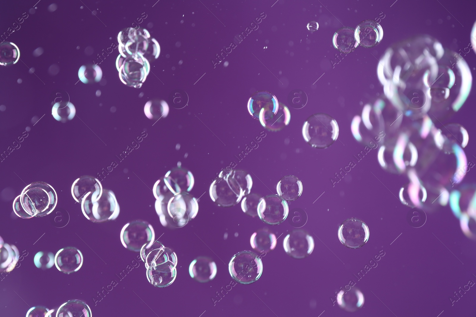 Photo of Beautiful transparent soap bubbles on purple background