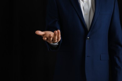 Man holding something on black background, closeup