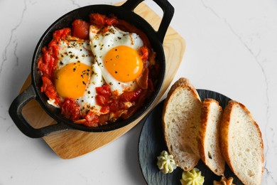 Photo of Tasty Shakshouka served on white marble table, flat lay