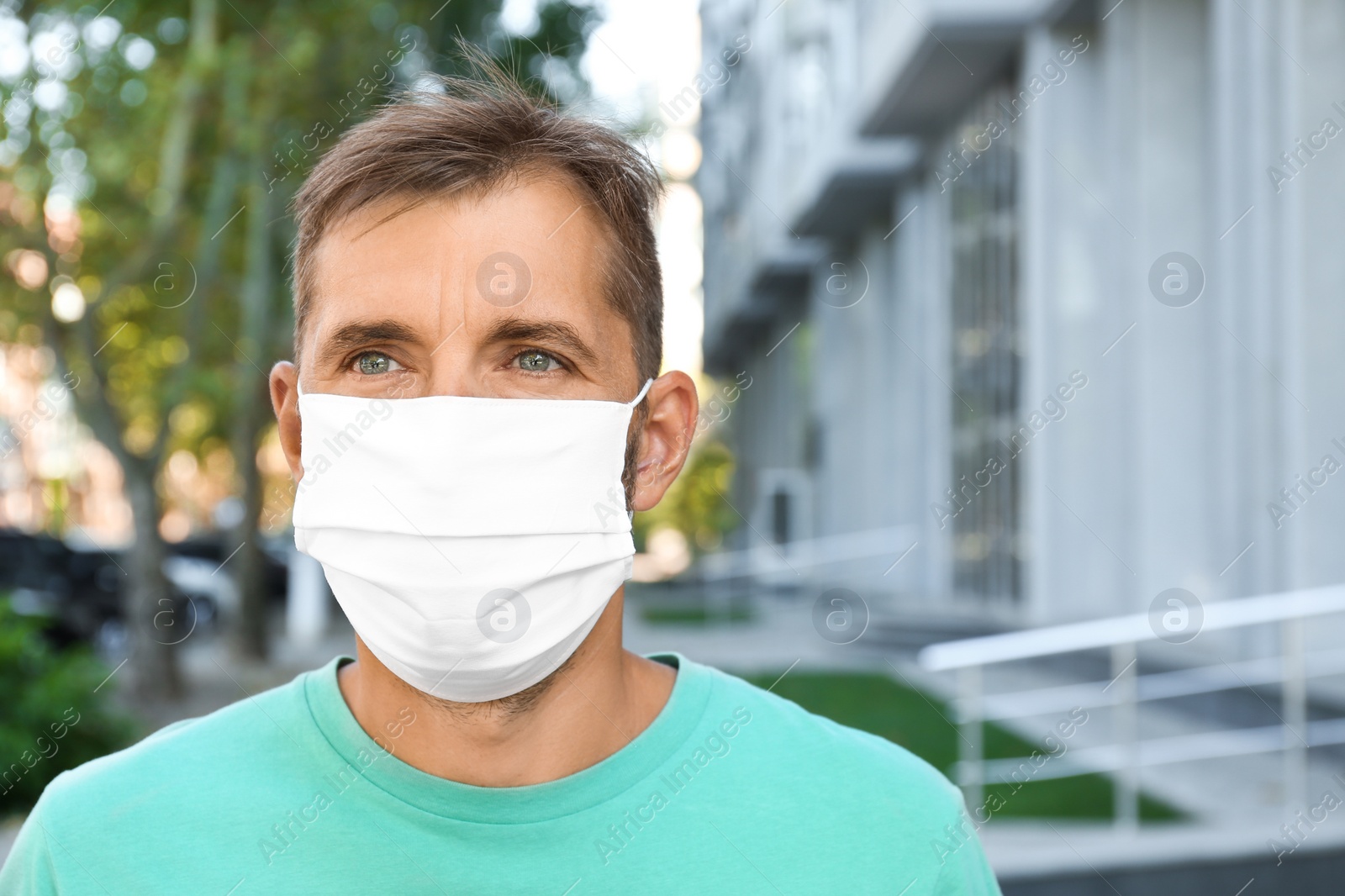 Photo of Man wearing handmade cloth mask outdoors, space for text. Personal protective equipment during COVID-19 pandemic