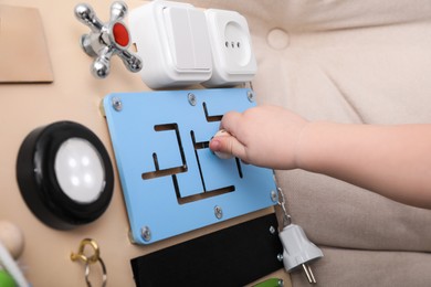 Photo of Little child playing with busy board on sofa, closeup