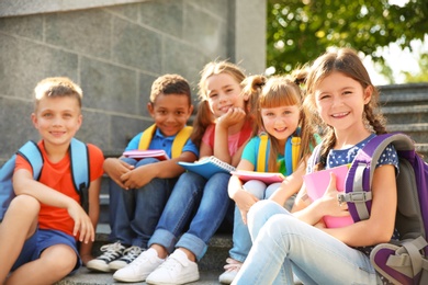 Cute little children with backpacks and notebooks outdoors. Elementary school