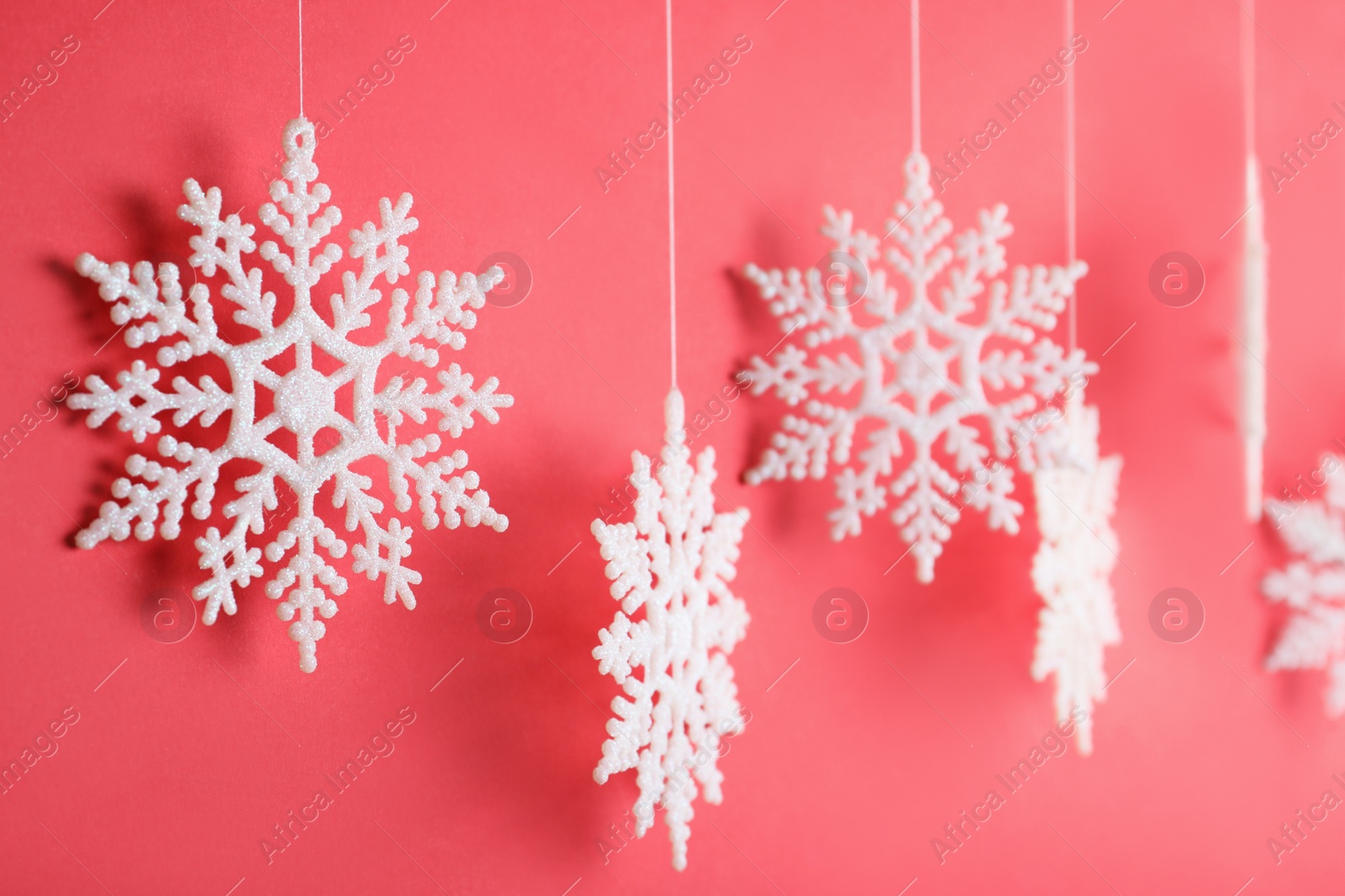 Photo of Beautiful decorative snowflake hanging on red background, closeup