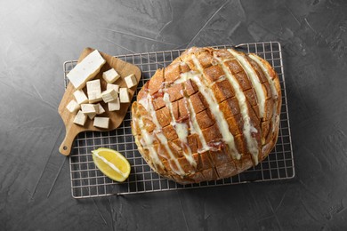 Photo of Freshly baked bread with tofu cheese and lemon on black table, top view