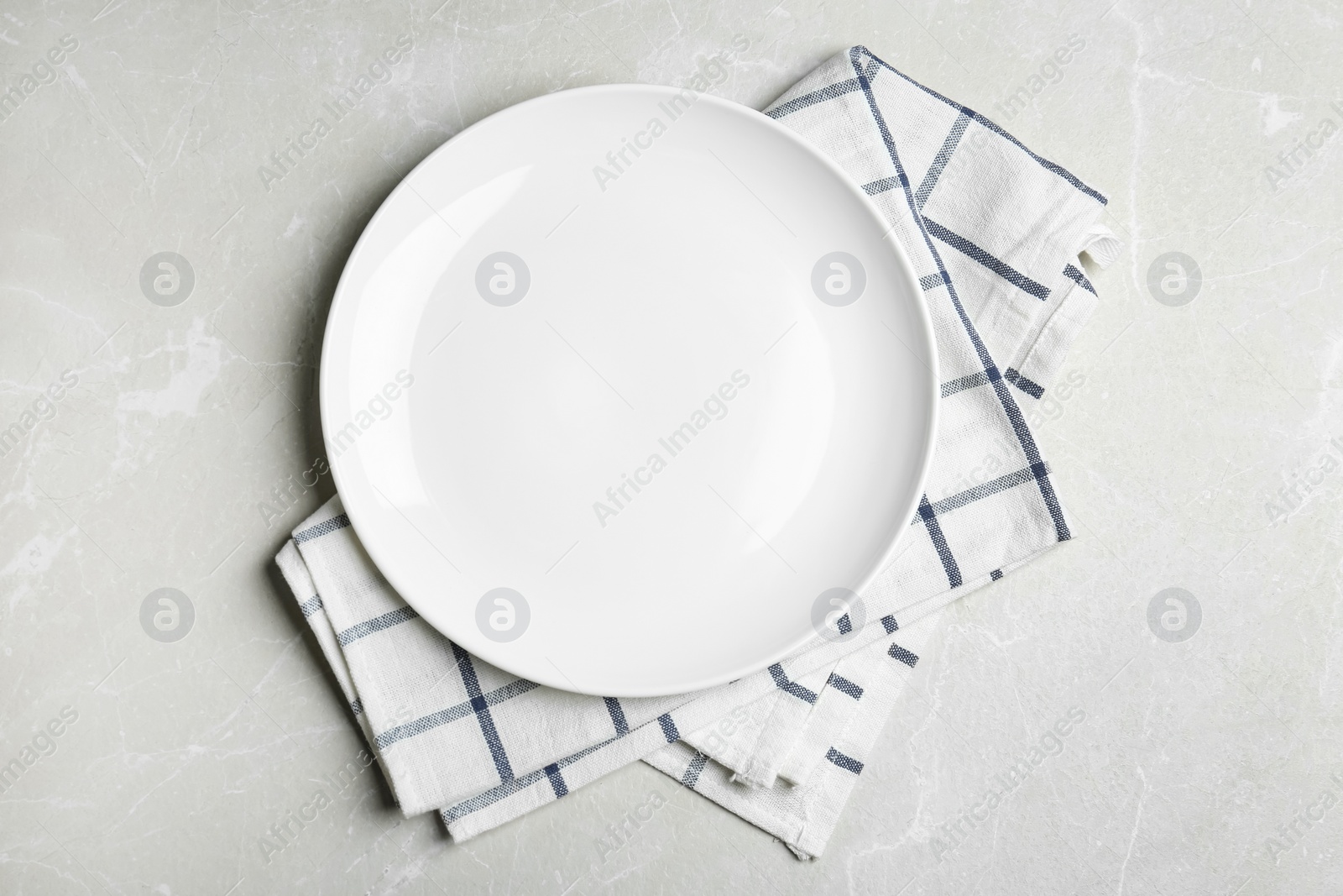 Photo of Empty white plate and napkin on light grey marble table, flat lay