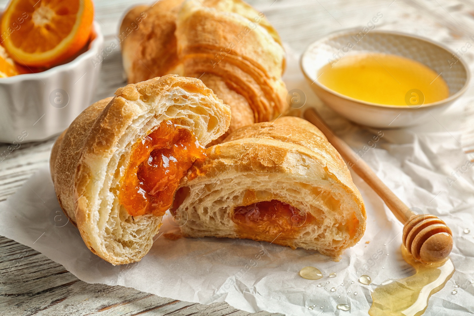 Photo of Tasty croissant with jam and honey on table, closeup