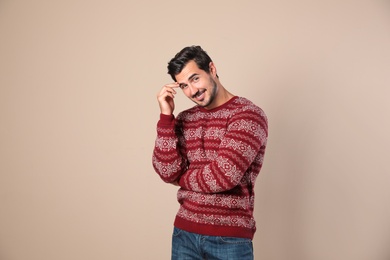 Portrait of happy man in Christmas sweater on beige background