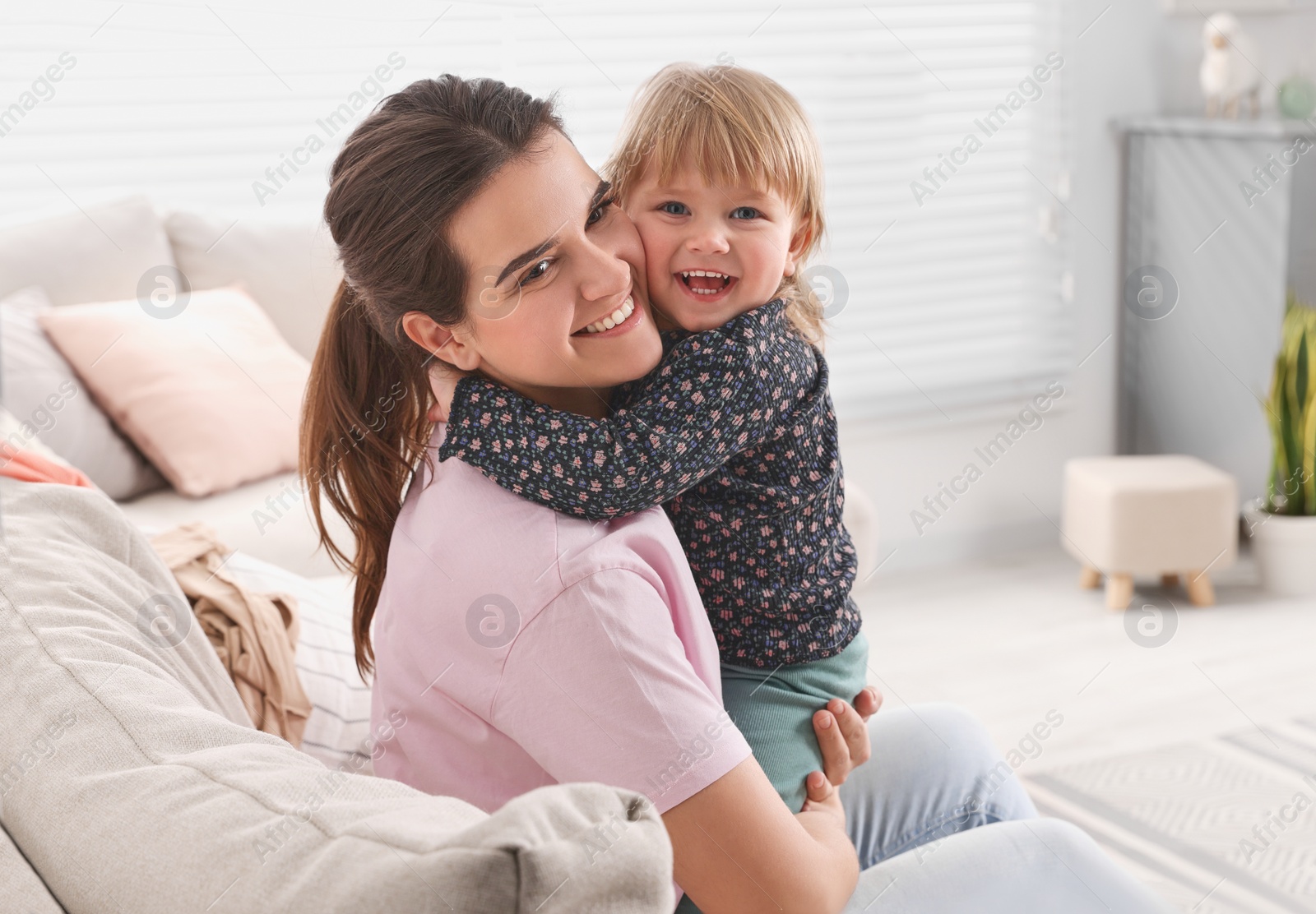 Photo of Mother with her cute little daughter on sofa at home, space for text