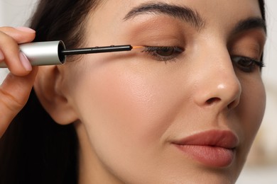 Photo of Beautiful woman applying serum onto her eyelashes, closeup. Cosmetic product