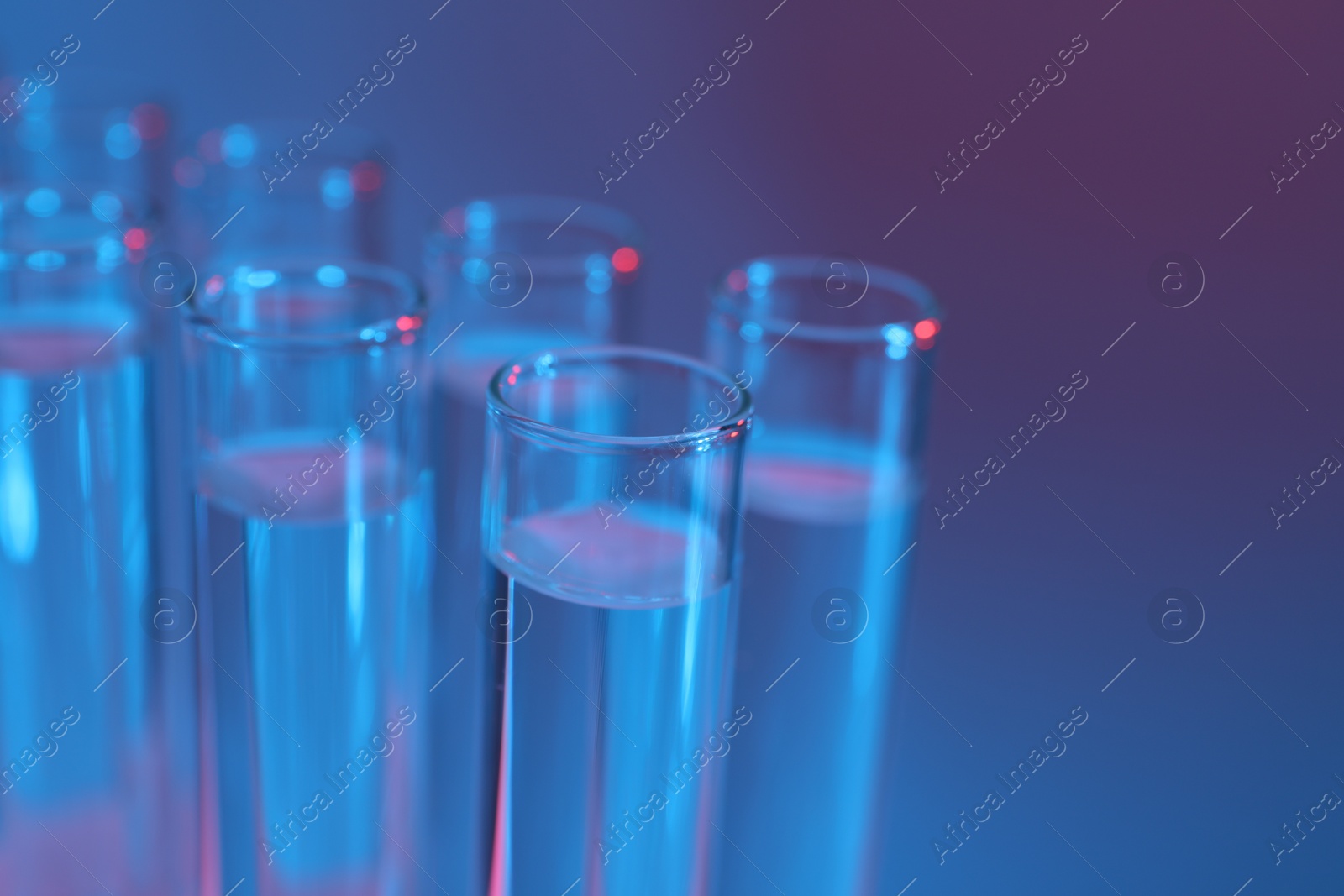 Photo of Many glass test tubes on color background, closeup