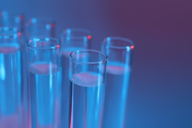 Photo of Many glass test tubes on color background, closeup