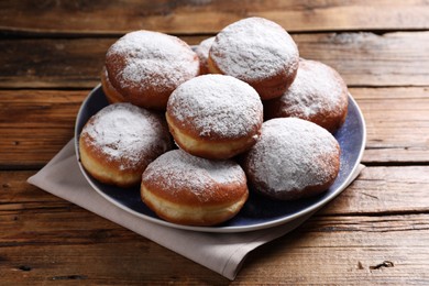 Delicious sweet buns with powdered sugar on wooden table