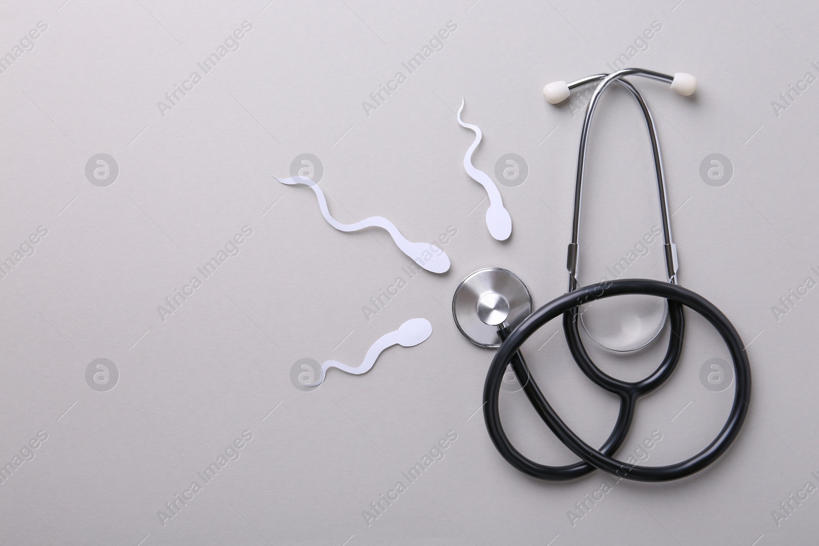 Photo of Reproductive medicine. Figures of sperm cells and stethoscope on gray background, flat lay with space for text