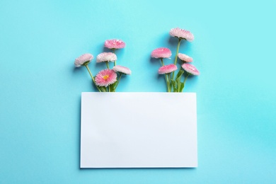 Photo of Flat lay composition with spring daisy flowers and card on color background. Space for text