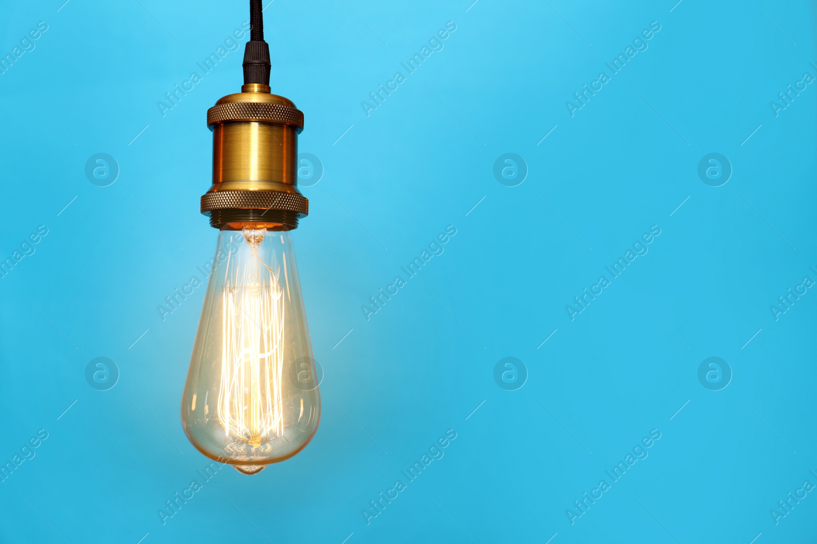 Photo of Pendant lamp with light bulb on color background, space for text