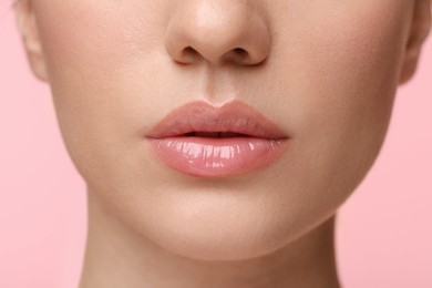Photo of Woman wearing beautiful lip gloss on pink background, closeup