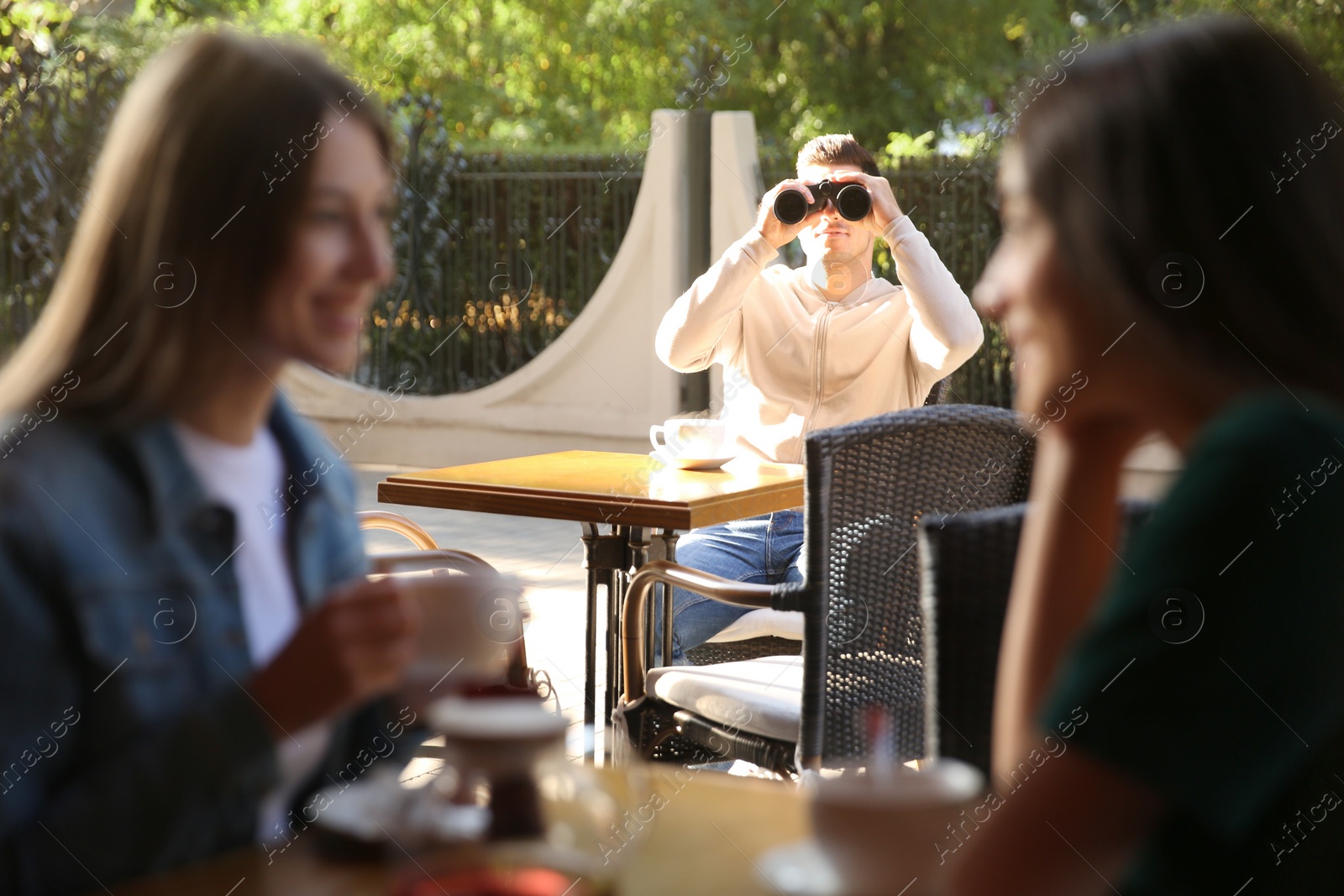 Photo of Jealous man spying on ex girlfriend in outdoor cafe