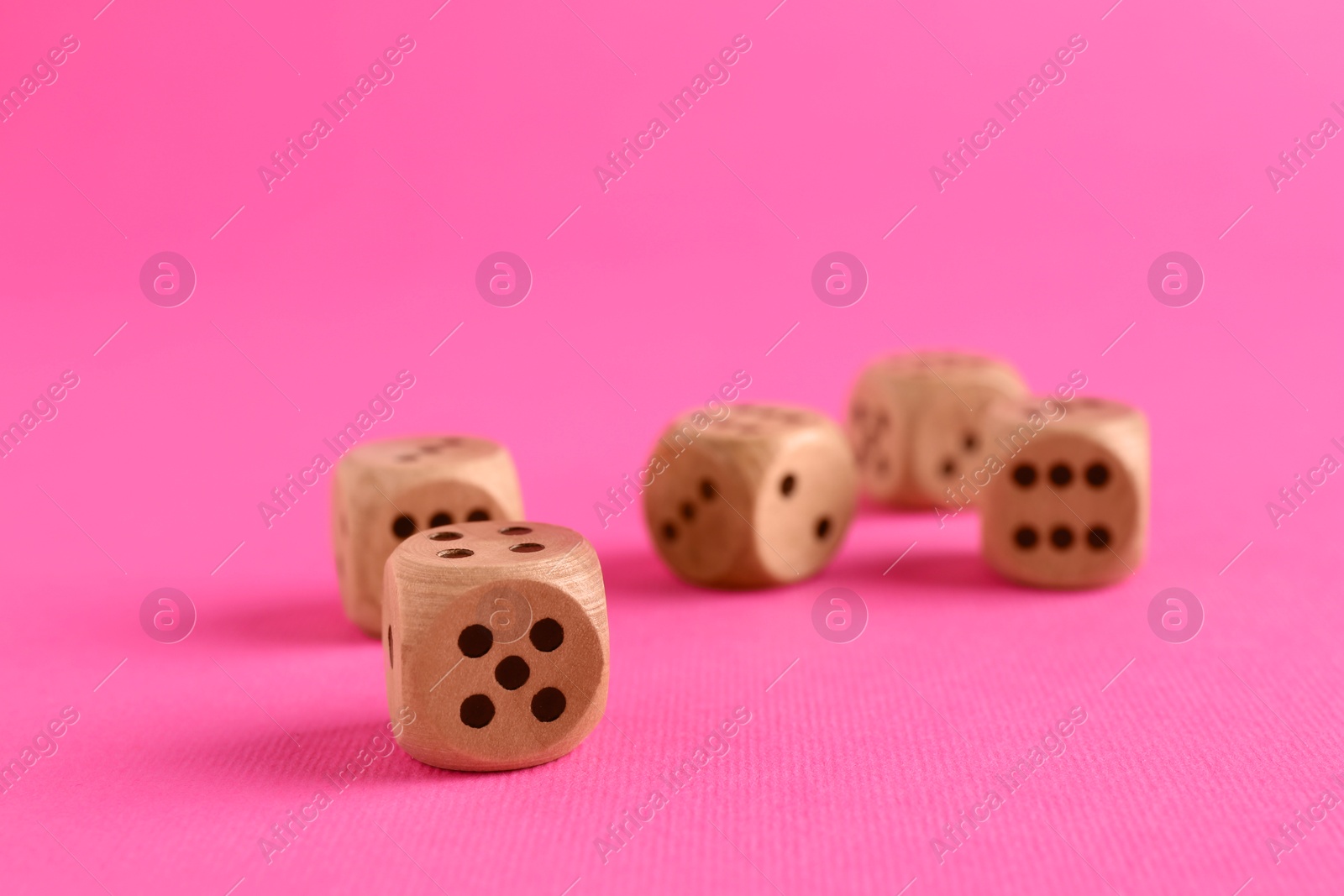 Photo of Many wooden game dices on pink background, closeup