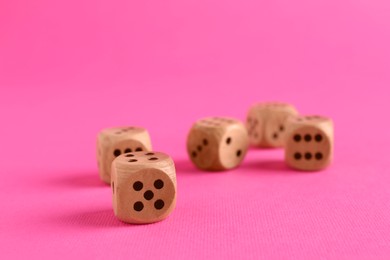 Photo of Many wooden game dices on pink background, closeup