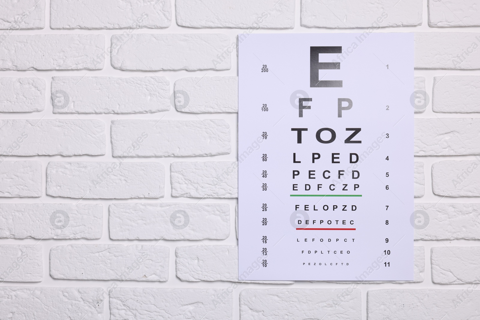 Photo of Vision test chart on white brick wall, space for text