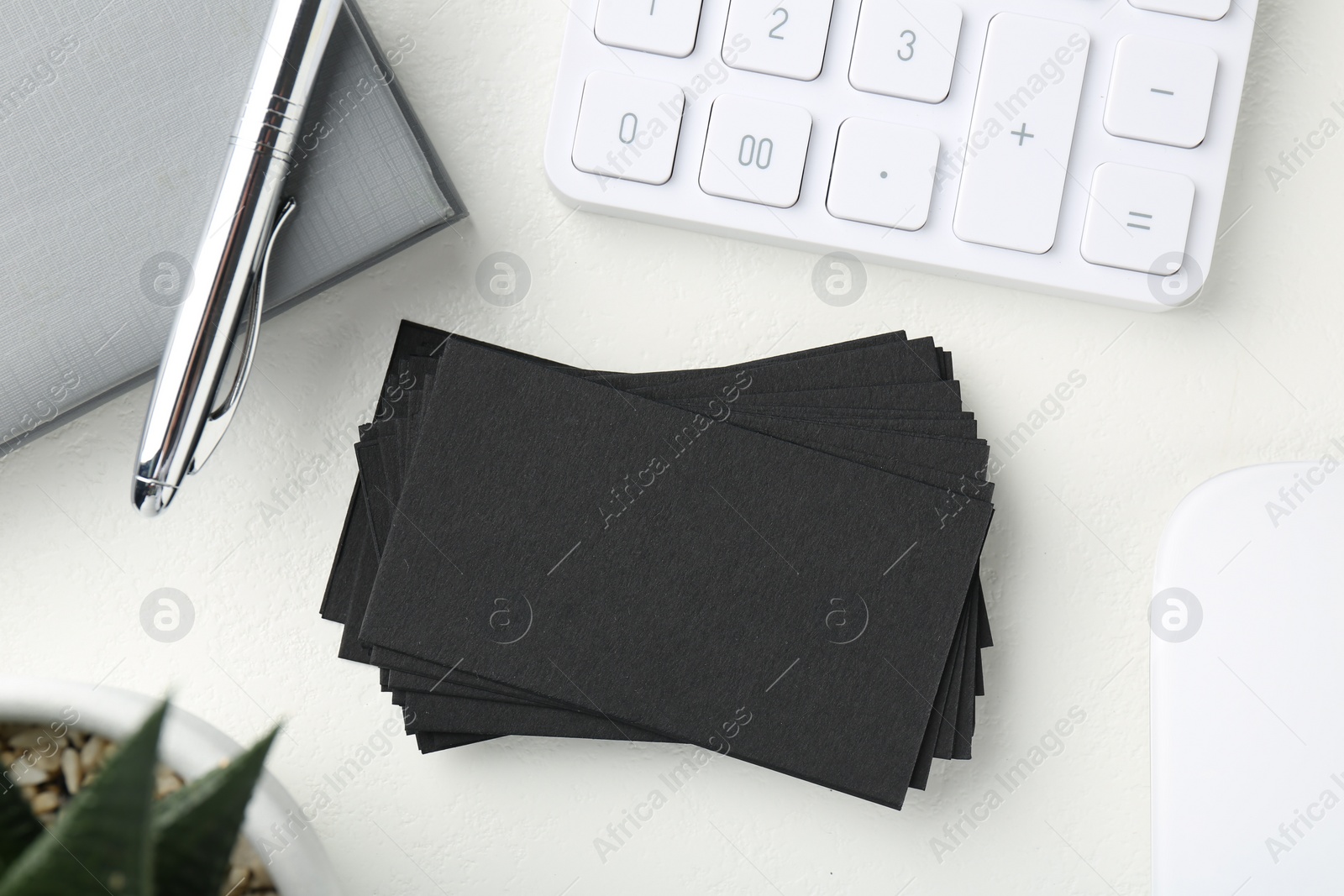 Photo of Blank black business cards, calculator, pen and notebook on white table, flat lay. Mockup for design