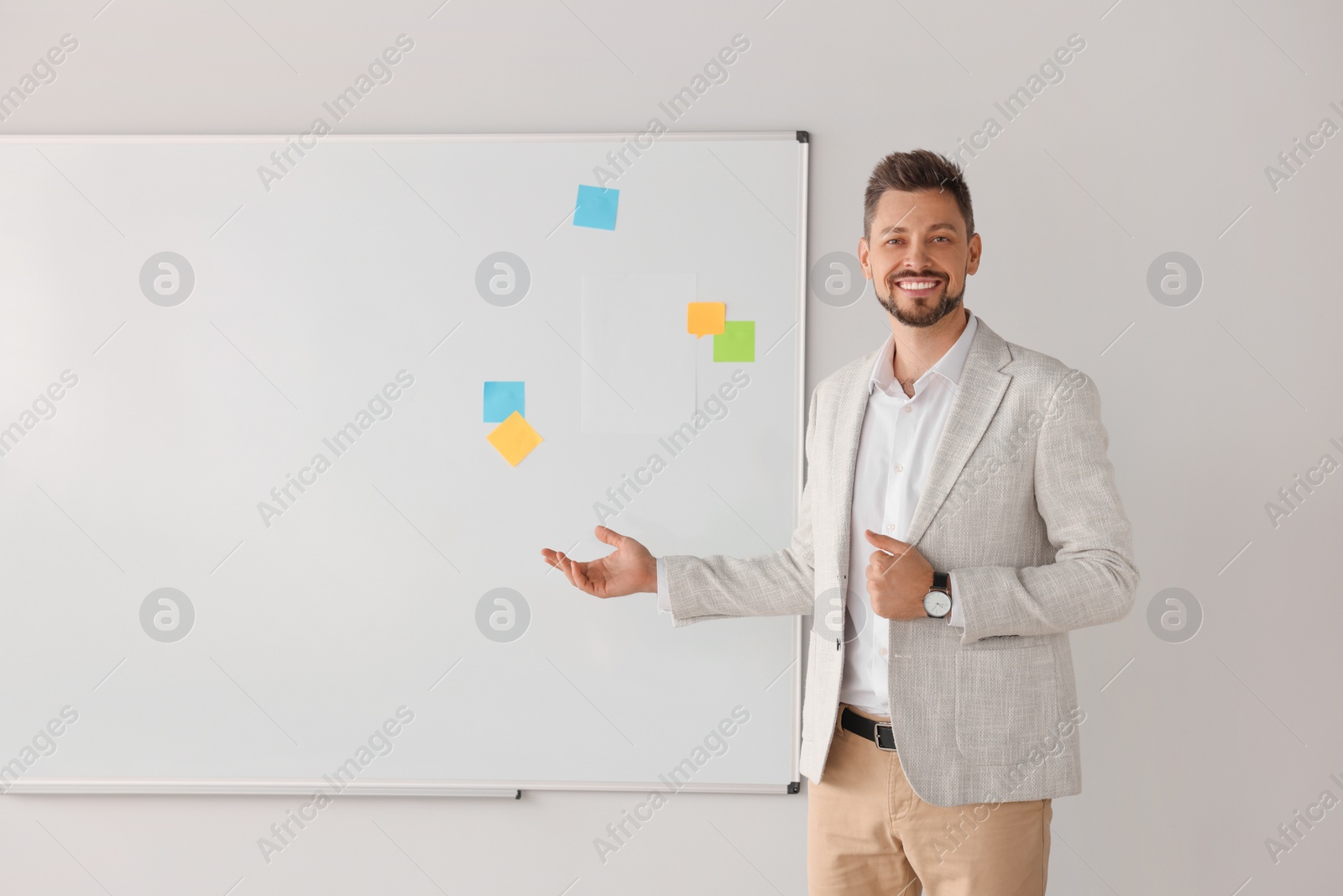 Photo of Happy teacher explaining something at whiteboard in classroom. Space for text