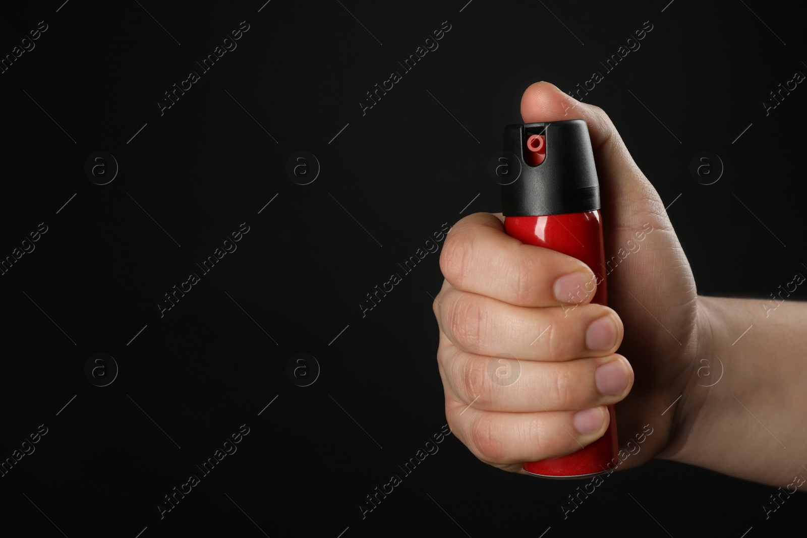 Photo of Man holding pepper spray on black background, closeup. Space for text