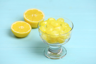 Photo of Tasty lemon drops in dessert bowl on light blue wooden table