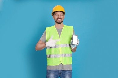 Male industrial engineer in uniform with phone on light blue background