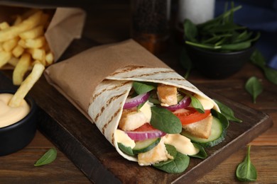 Photo of Delicious shawarma with chicken meat, fresh vegetables and spinach on wooden table, closeup