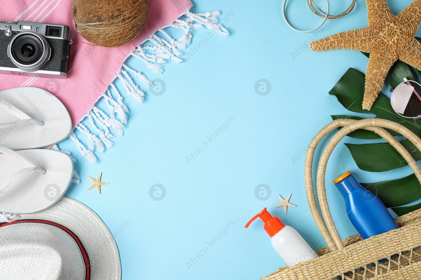 Photo of Frame with beach accessories and space for text on light blue background, flat lay